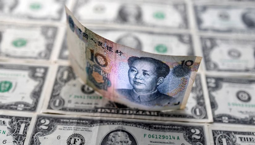 ورقة من عملة اليوان الصيني تعلو دولارات أمريكية- صورة أرشيفية 